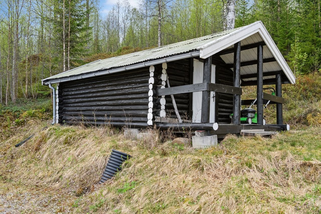 Tømmerstue med overbygget inngangsparti/terrasseplatting. Denne benyttes i dag som bod. Galleribilde