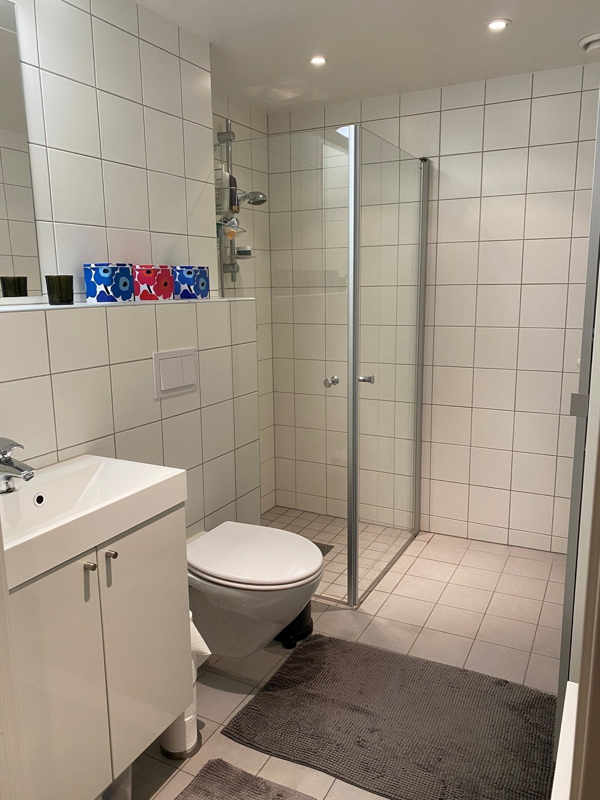 Flott flislagt bad med dusjhjørne, vegghengt WC, servant og baderomsinnredning. Galleribilde