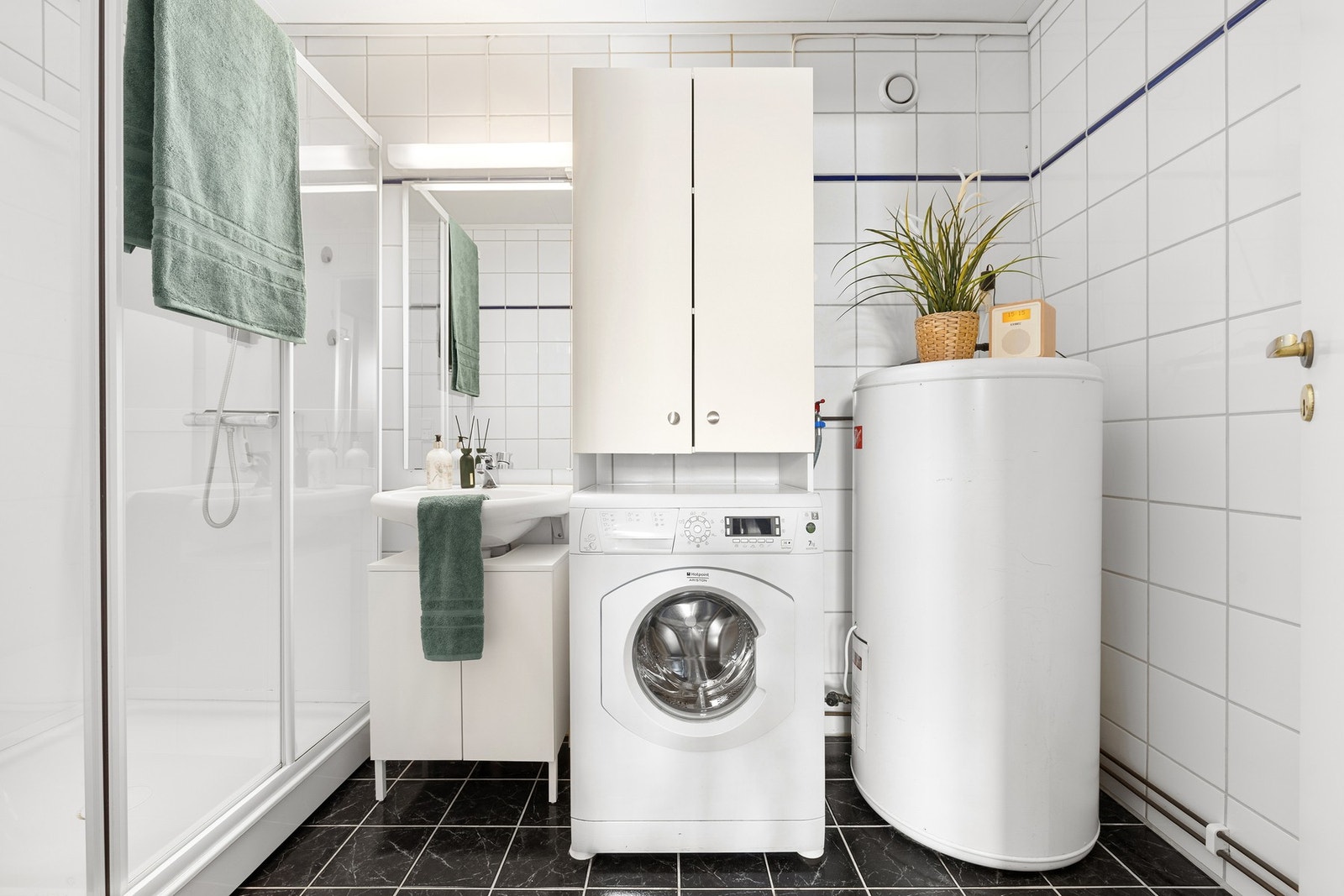 Badet inneholder servant, speil, toalett, dusjkabinett, opplegg for vaskemaskin og varmtvannsbereder. Galleribilde