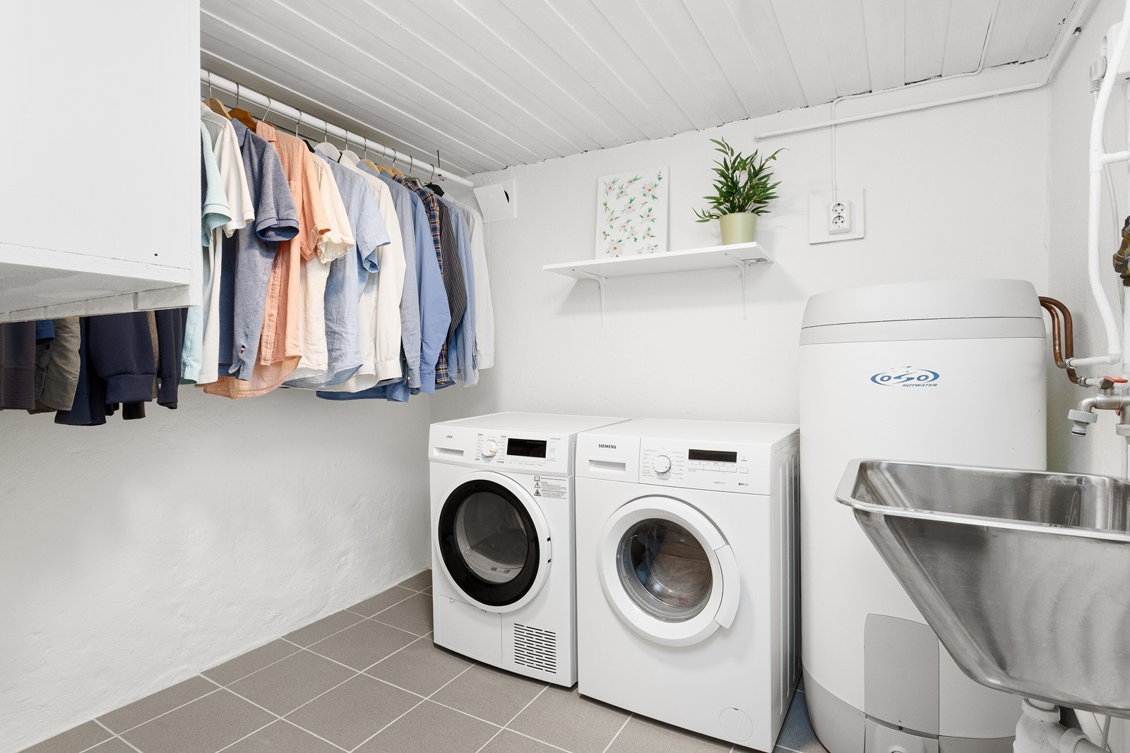Praktisk og romslig vaskerom med plass for klesvask og oppheng. Rommet er utstyrt med utslagsvask og opplegg for vaskemaskin. Galleribilde
