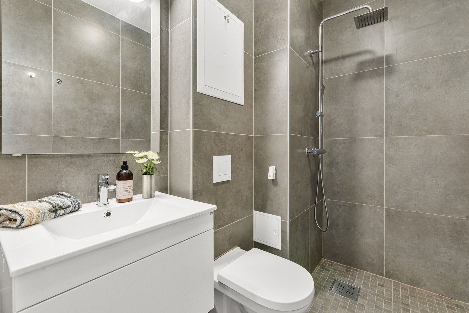 Badet holder en moderne standard med vegghengt WC, servant med skuffer og speil med belysning. Galleribilde