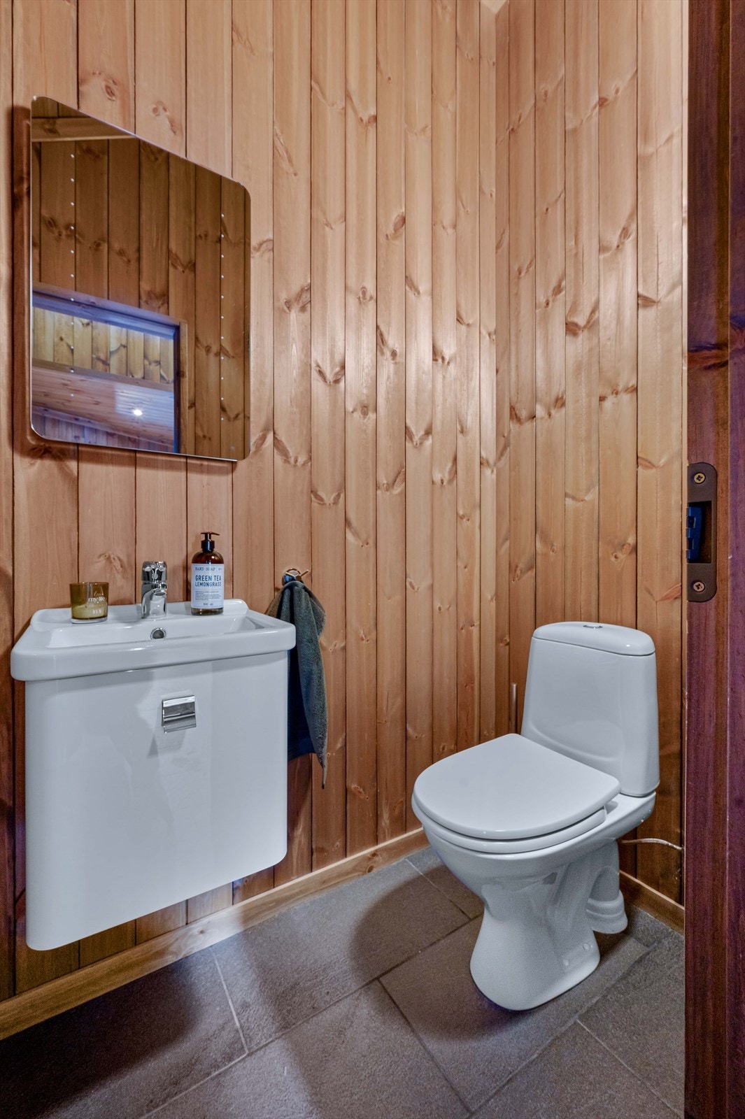 Separat toalettrom med fliser på gulvet og stående panel på veggene. Galleribilde