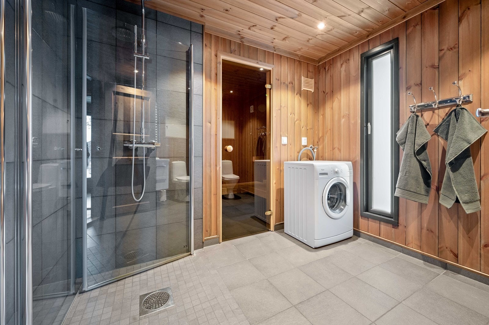 Romslig baderom med flislagt gulv med varmekabler, downlights i himling, opplegg for vaskemaskin og badstue. Galleribilde