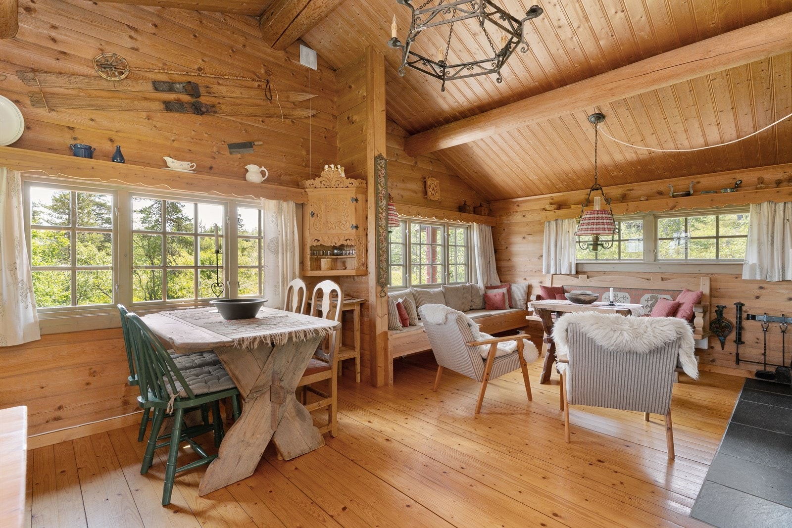 Innbydende stue med gulv av furu og laftet trepanel på vegg. Galleribilde