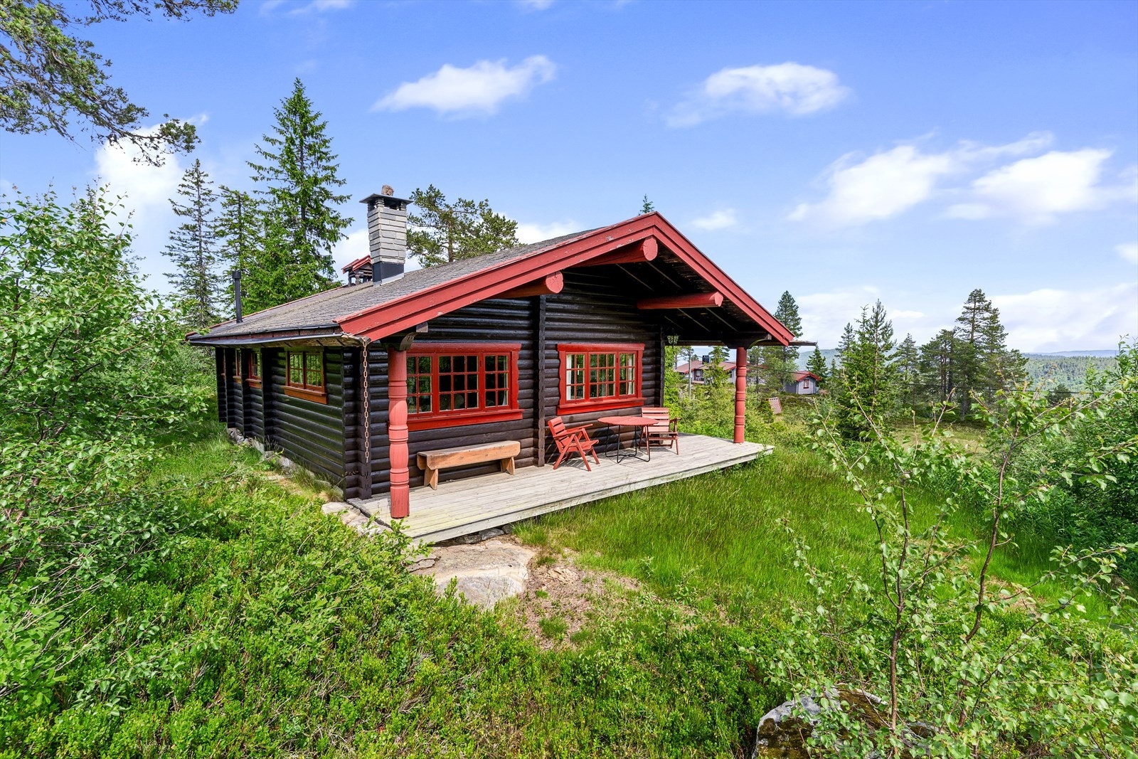 Hytta oser av tradisjon med mørkbeiset tømmer, vakre røde detaljer og utskårne søyler som gir den et autentisk norsk preg. Galleribilde