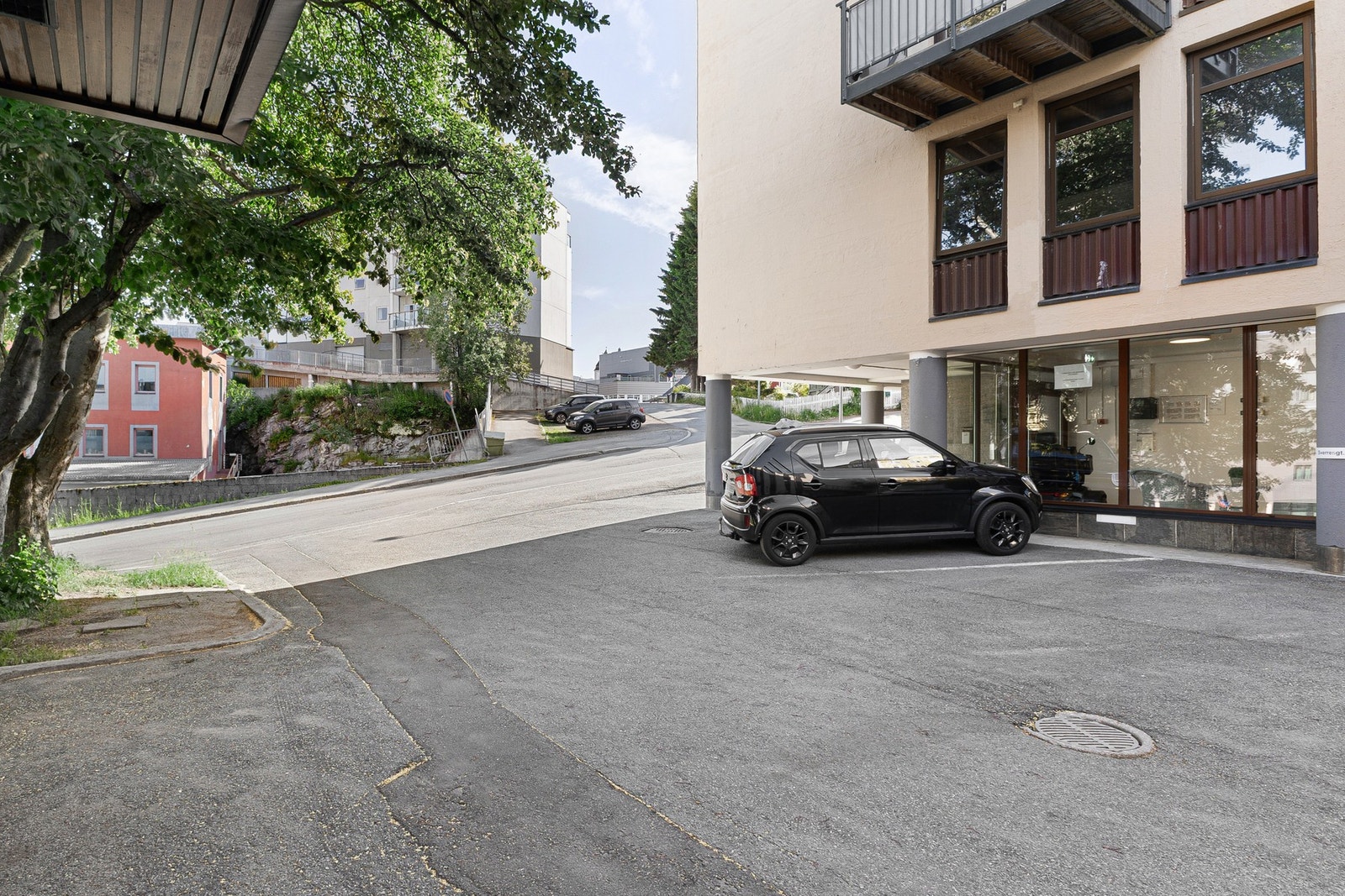 Asfalterte parkeringsplasser utenfor leilighetsbygget - parkering må søkes styre Galleribilde
