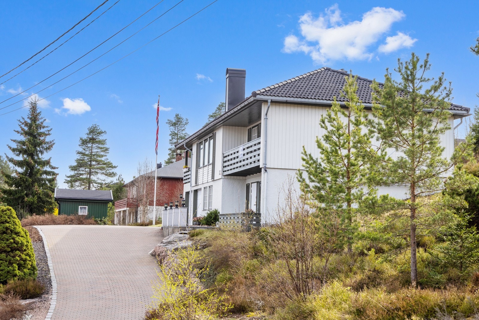 Tomten er pent opparbeidet med diverse prydbusker, beleggningsstein, plenareal, trær og naturtomt i bakkant Galleribilde