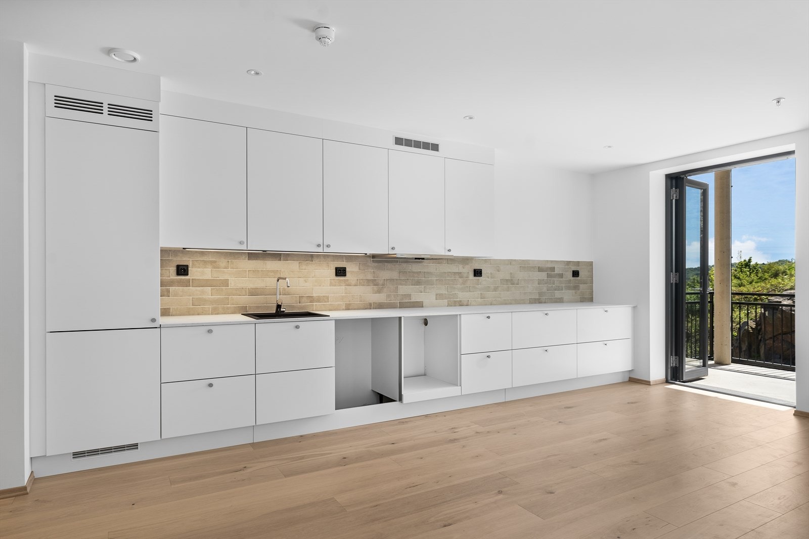 Hvit tidløs kjøkkeninnredning fra Strai kjøkken. Flislagt mellom benkeplate og overskap. Galleribilde