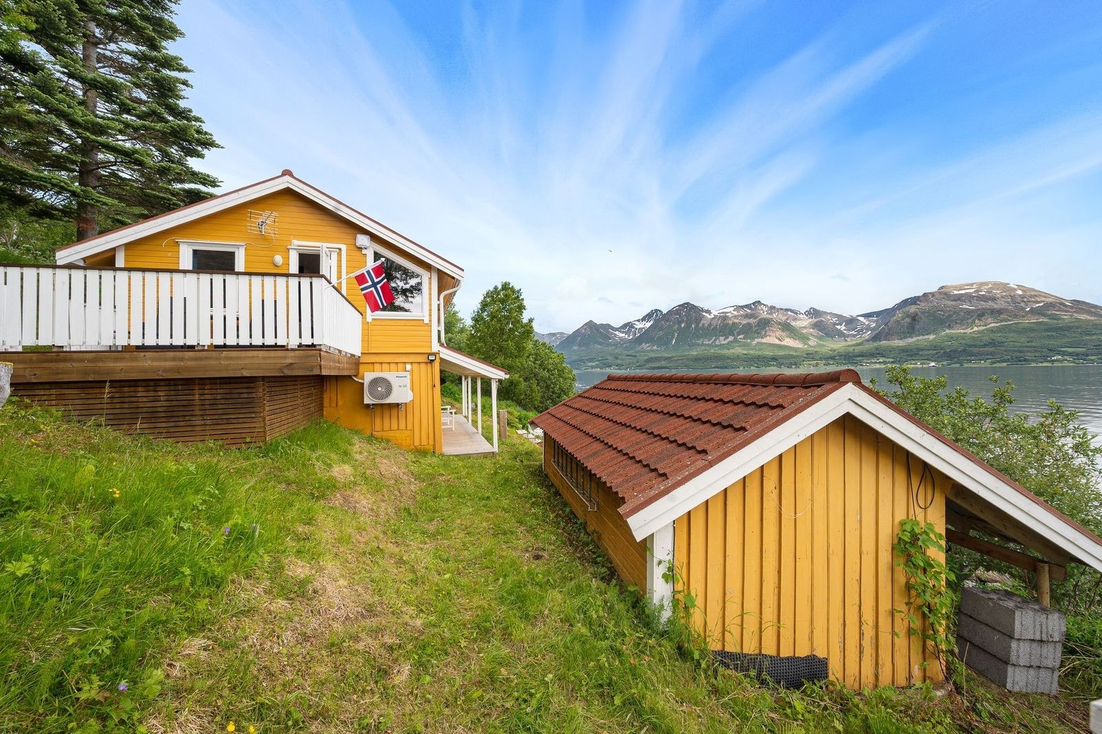 Sjarmerende gul hytte med naust og aneks beliggende nede ved sjøen. Galleribilde