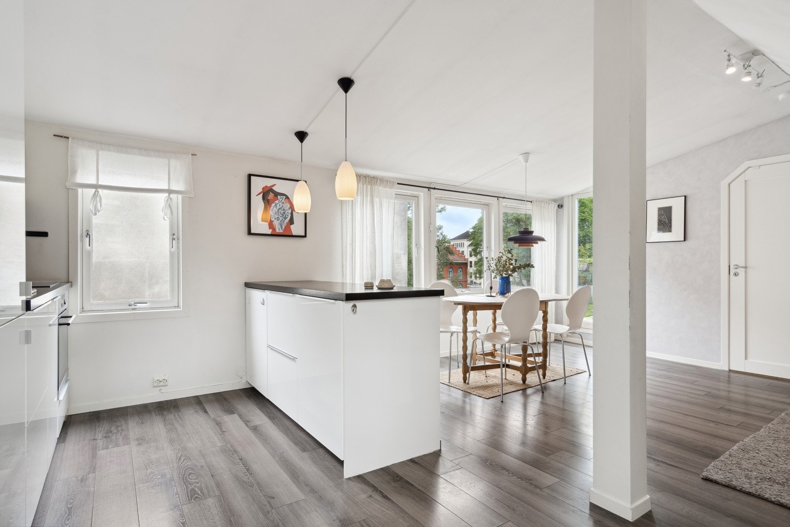 Kjøkkenet er tilbaketrukket i rommet og har en tidløs innredning med hvite fronter og mørk benkeplate. Galleribilde