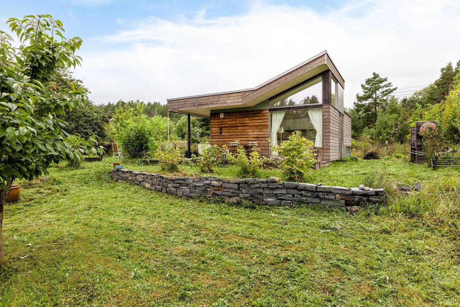 Tomten er relativt relativt flat og er opparbeidet med grøntområder i to nivåer. Nivåforskjellen er opparbeidet med steinmur. Galleribilde