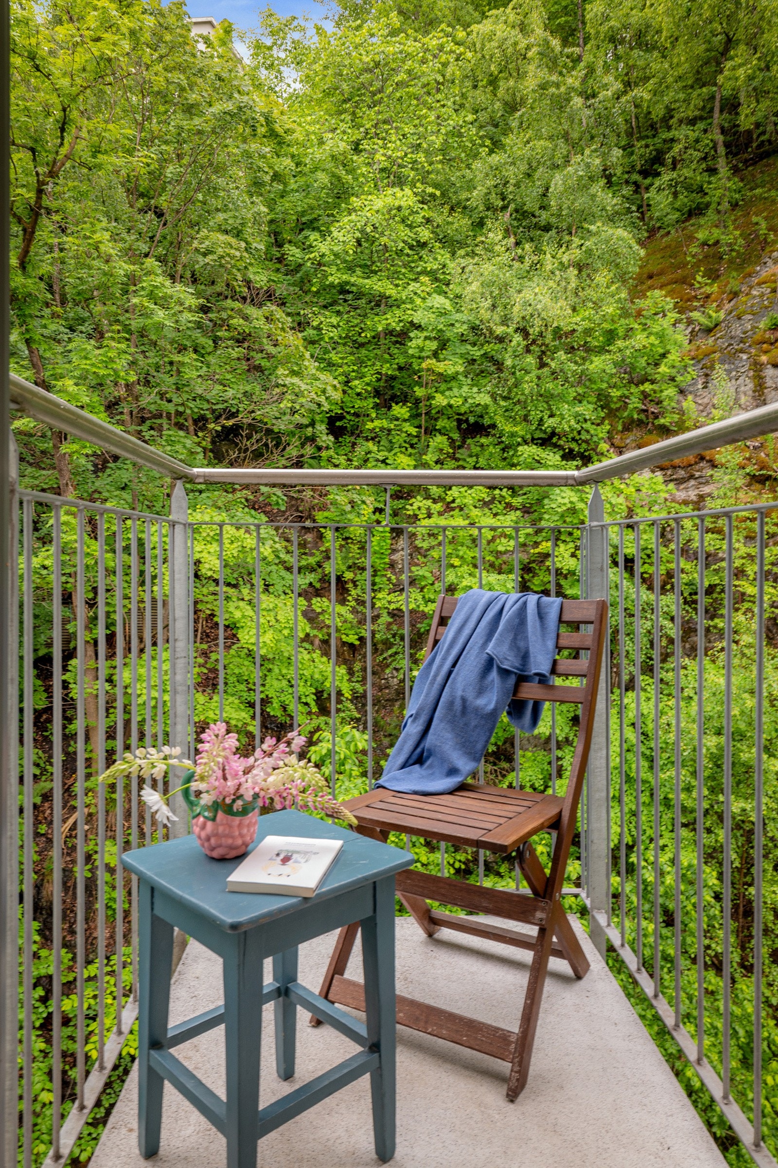 Balkongene vender mot fjellvegg med frodig vegetasjon og et yrende fugleliv ifølge selger. Galleribilde