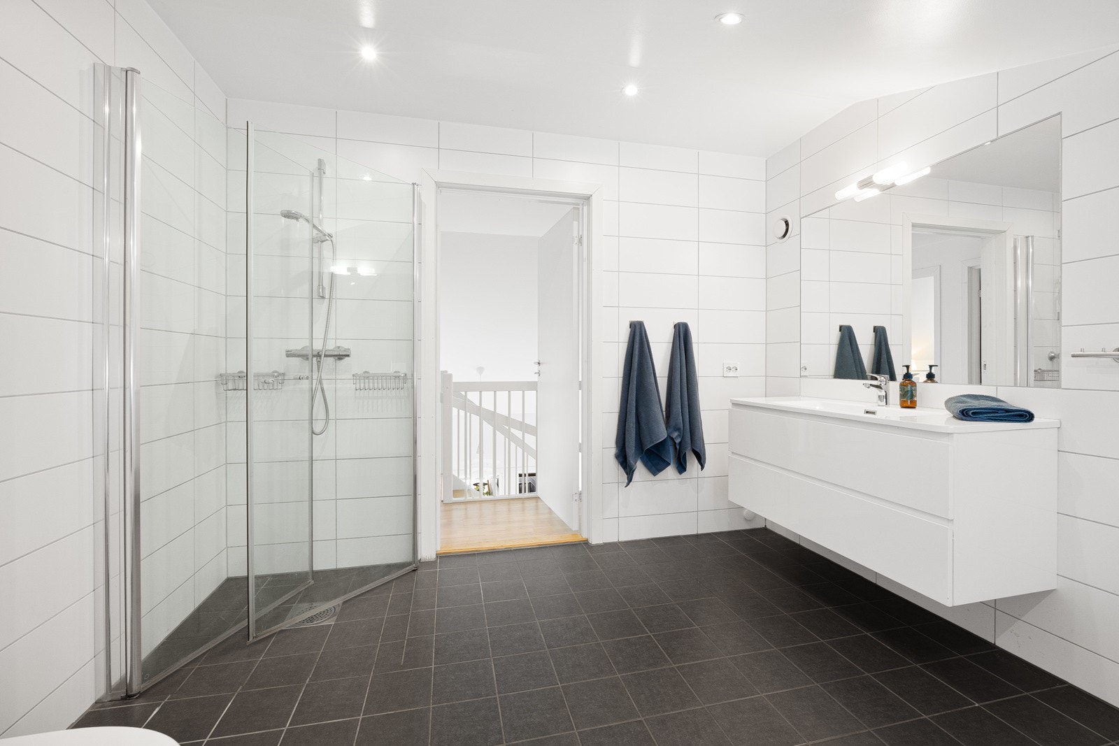 Badet i andre etasje er innredet med en dusjnisje, badekar, moderne servantmøbel, speil og veggmontert toalett. Galleribilde