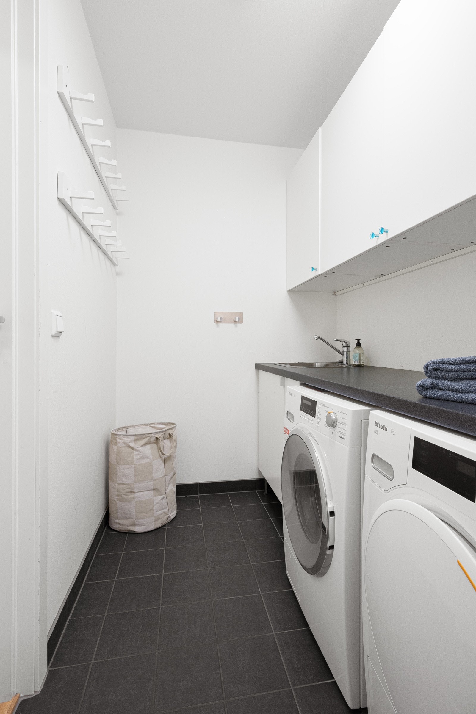 Vaskerommet har adkomst fra hallen og er pent innredet med fliser på gulv, mørk benk, vaskekum og hvite skap. Innen for finner du romslig bod. Galleribilde