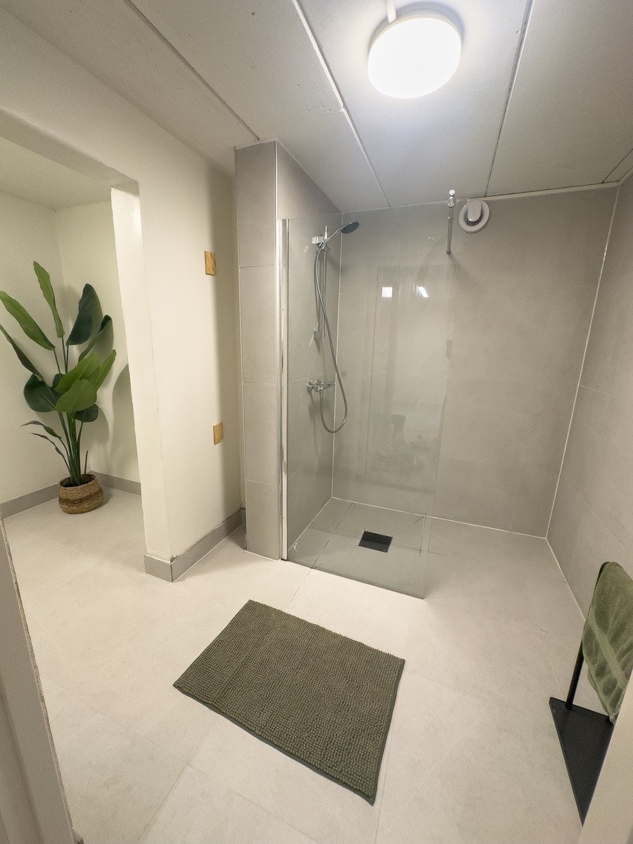 Bad med stor dusj, videre inn på badet er toalett og servant Galleribilde