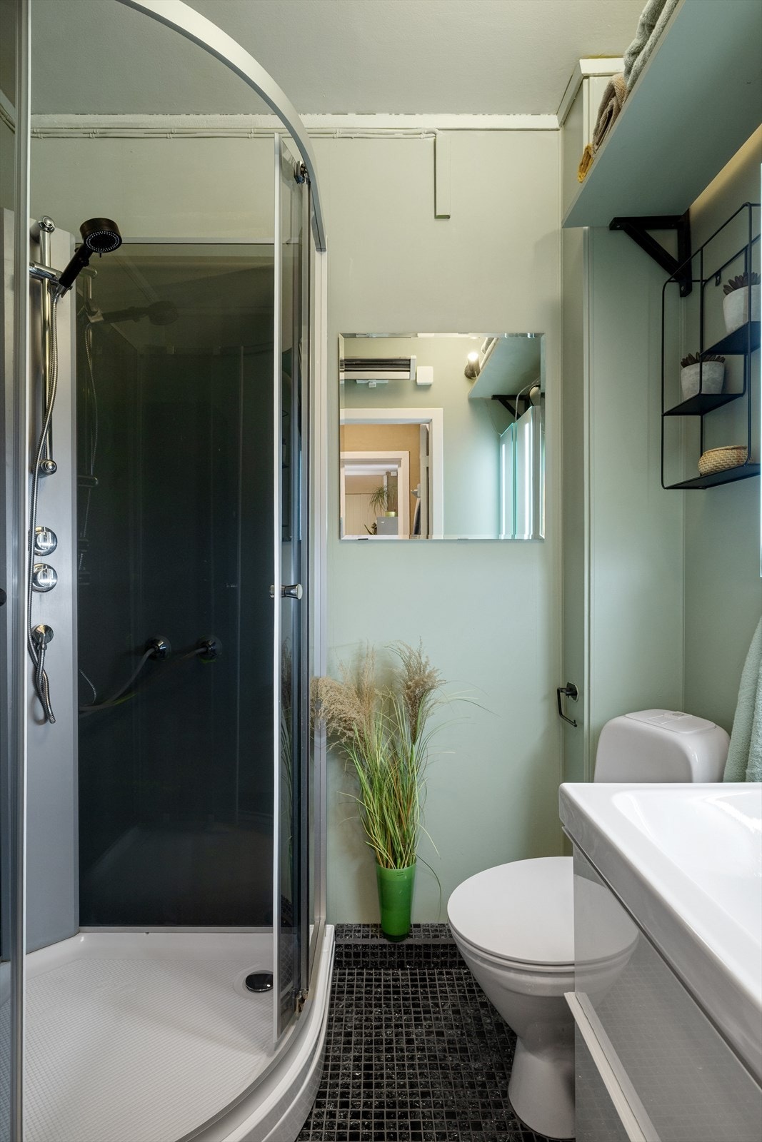 Badet er utstyrt med dusjkabinett med buet dør og farget glass. Galleribilde