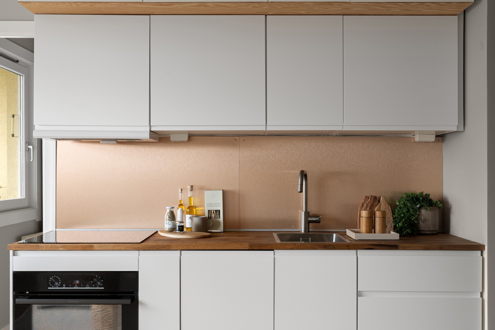 Innredningen har hvite glatte fronter (nye i 2025) og heltre benkeplate av eik med nedfelt kum i rustfritt stål. Galleribilde