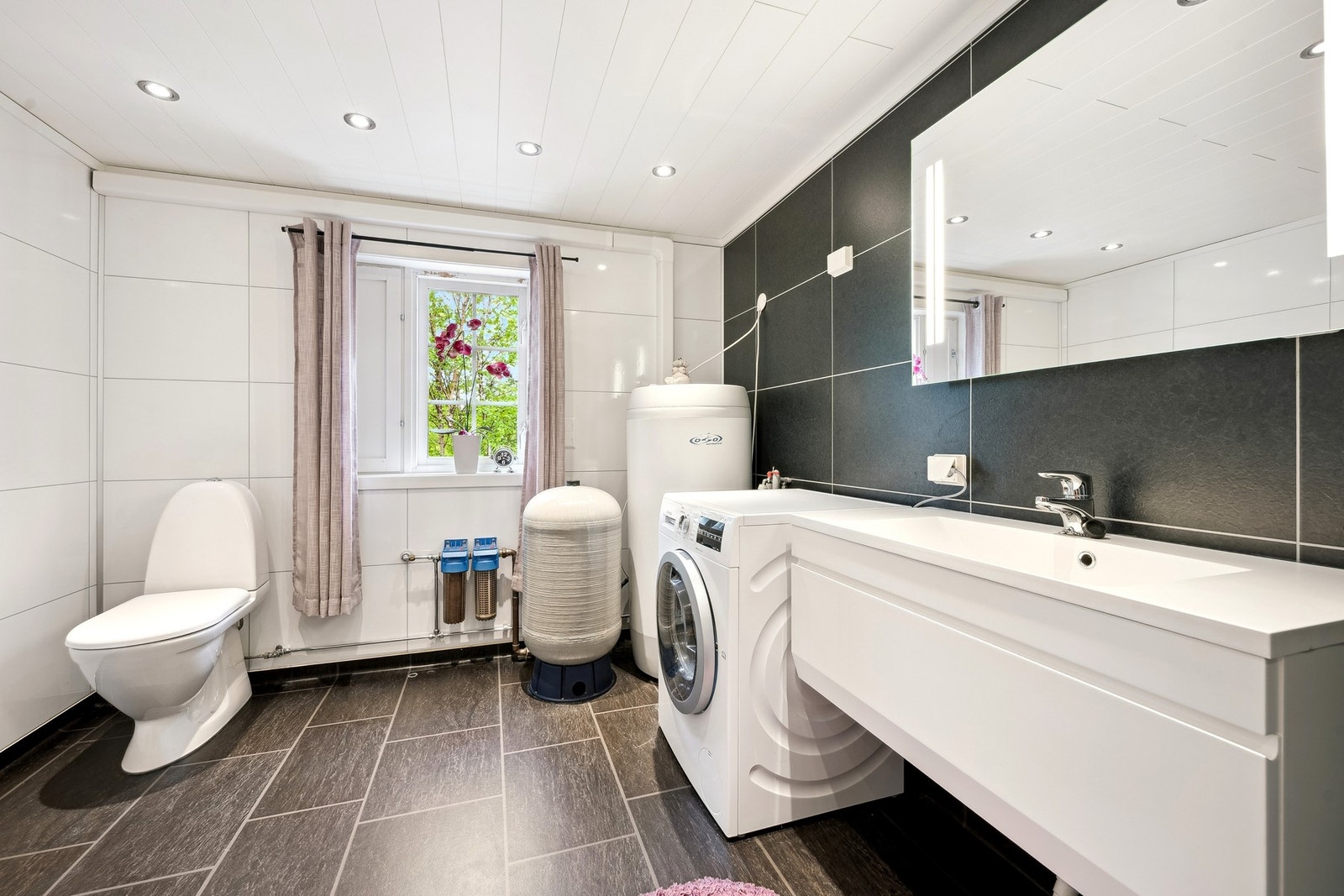 Badet er utstyrt med toalett, opplegg for vaskemaskin, baderomsinnreding, varmtvannsbereder, vannpumpe og dusj Galleribilde