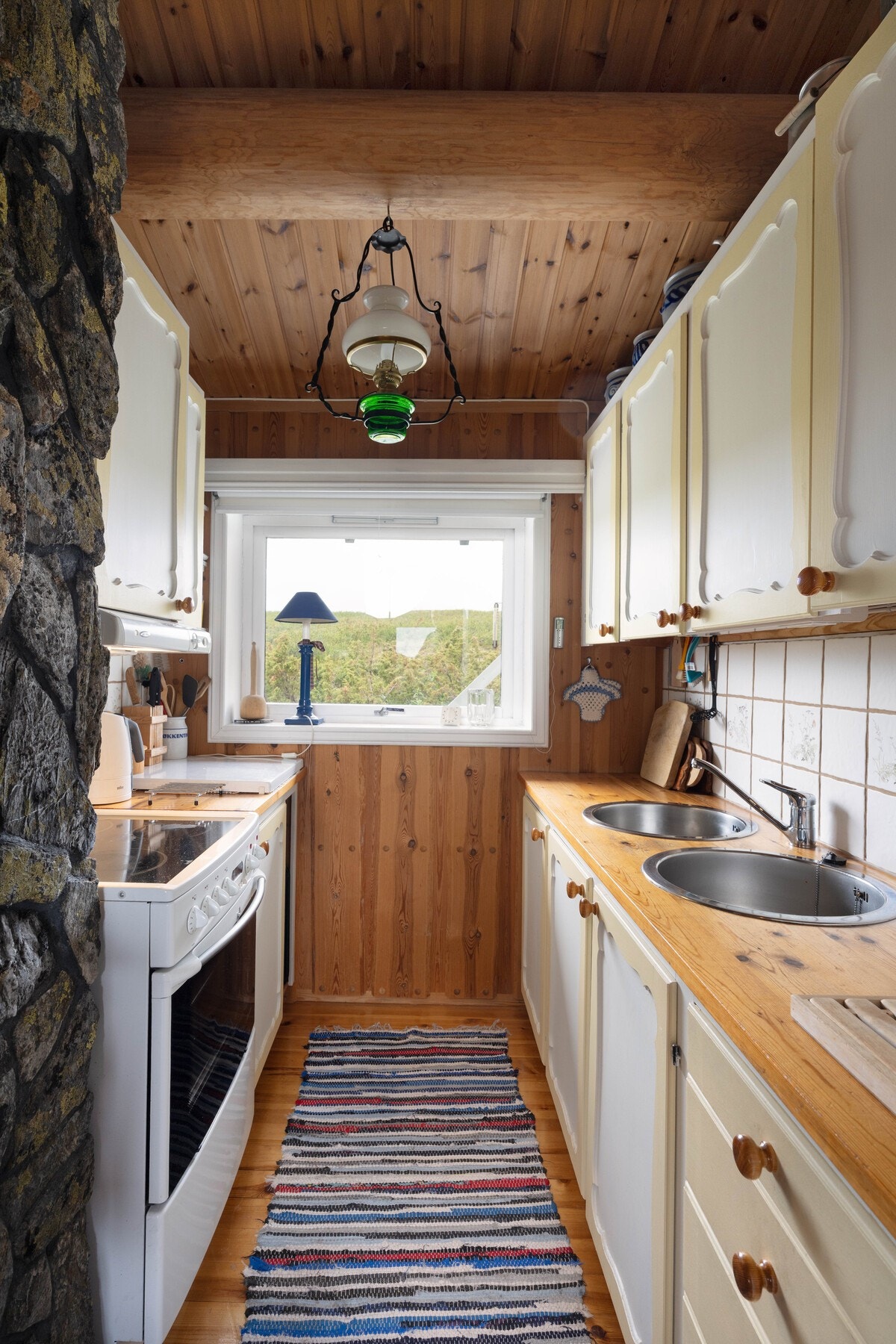 De hvite, profilerte frontene gir et lyst og tidløst preg, mens den solide heltre benkeplaten tilfører en varm og naturlig følelse til rommet. Galleribilde