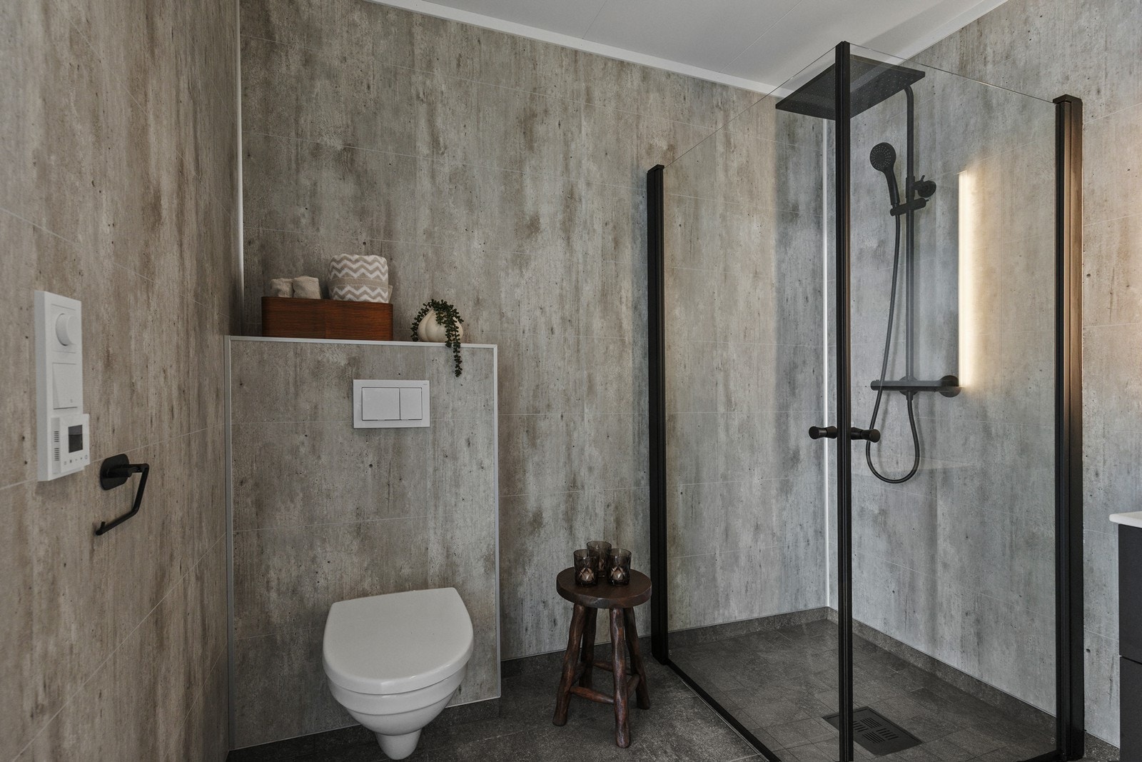 Badet har sorte fliser på gulv, vegghengt toalett, og dusjhjørnet er utstyrt med regndusj fra Vikingbad. Galleribilde