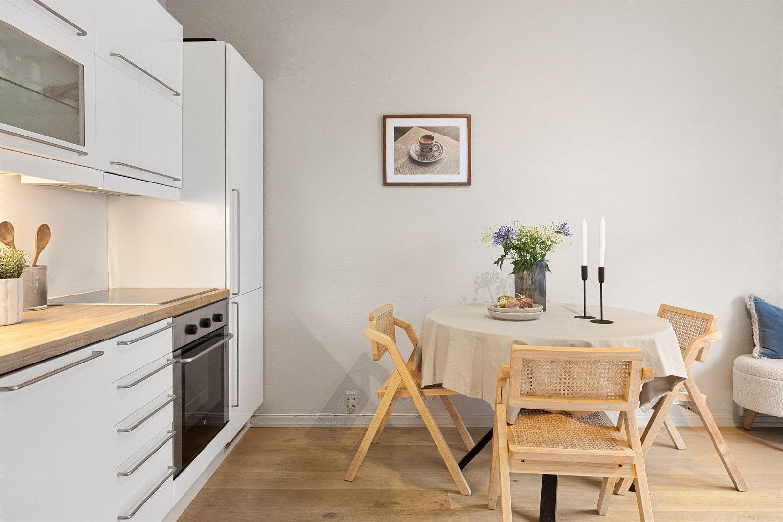 Smakfull kjøkkeninnredning med hvite, glatte fronter og benkeplate i tre. Kum og togreps blandebatteri. Kjøkkenet er utstyrt med integrerte hvitevarer som komfyr, platetopp, oppvaskmaskin, kjøl/ fryseskap samt ventilator over kokesone. Galleribilde