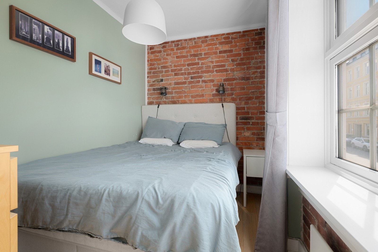 Leiligheten har et hyggelig soverom med plass til seng og nattbord. Det er sjarmerende teglstein på veggen. Galleribilde