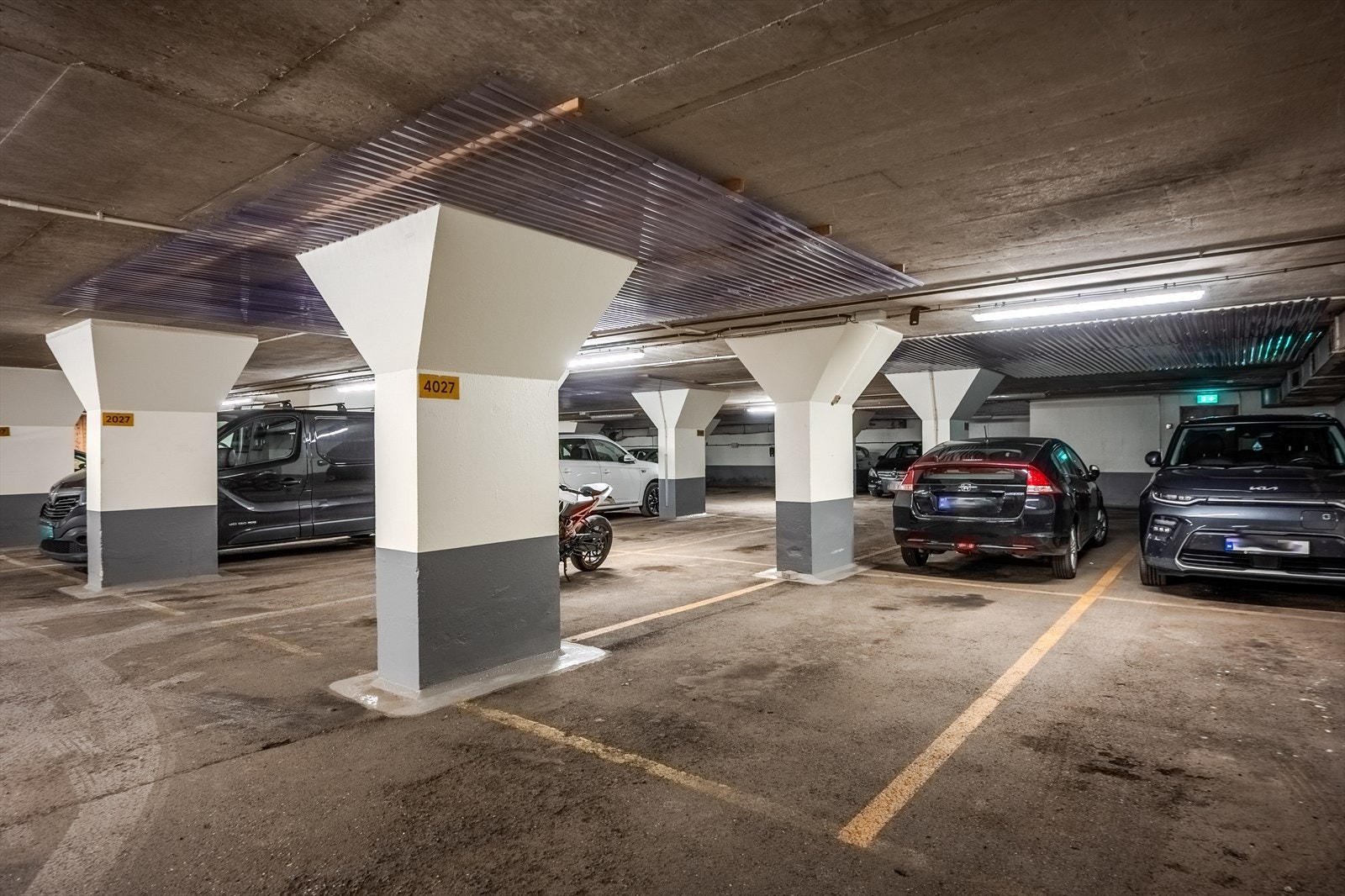Det medfølger en parkeringsplass i lukket garasjeanlegg merket 4027. I 2020/21 ble det installert infrastruktur for elbillading til samtlige parkeringsplasser i parkeringshusene. Andelseieren må selv bekoste laderen. Bestillingen gjøres via styret. Galleribilde
