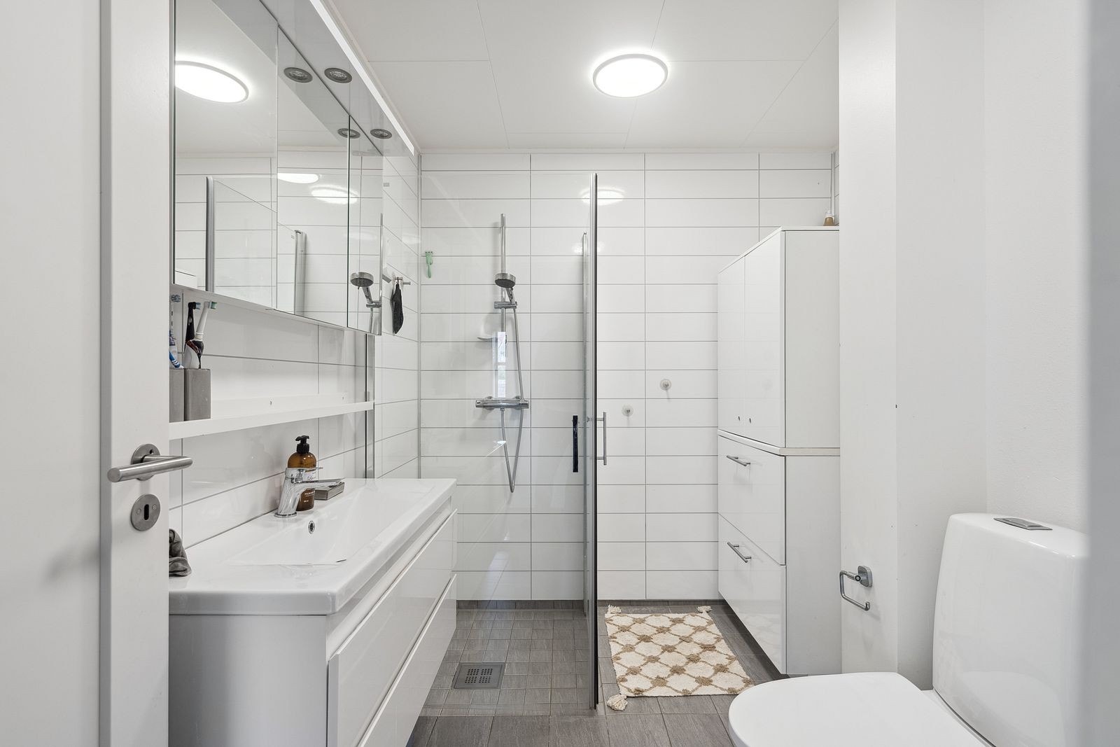 Baderom med fliser på gulv og plater på vegg. Inkl. tørketrommel og vaskemaskin. Galleribilde