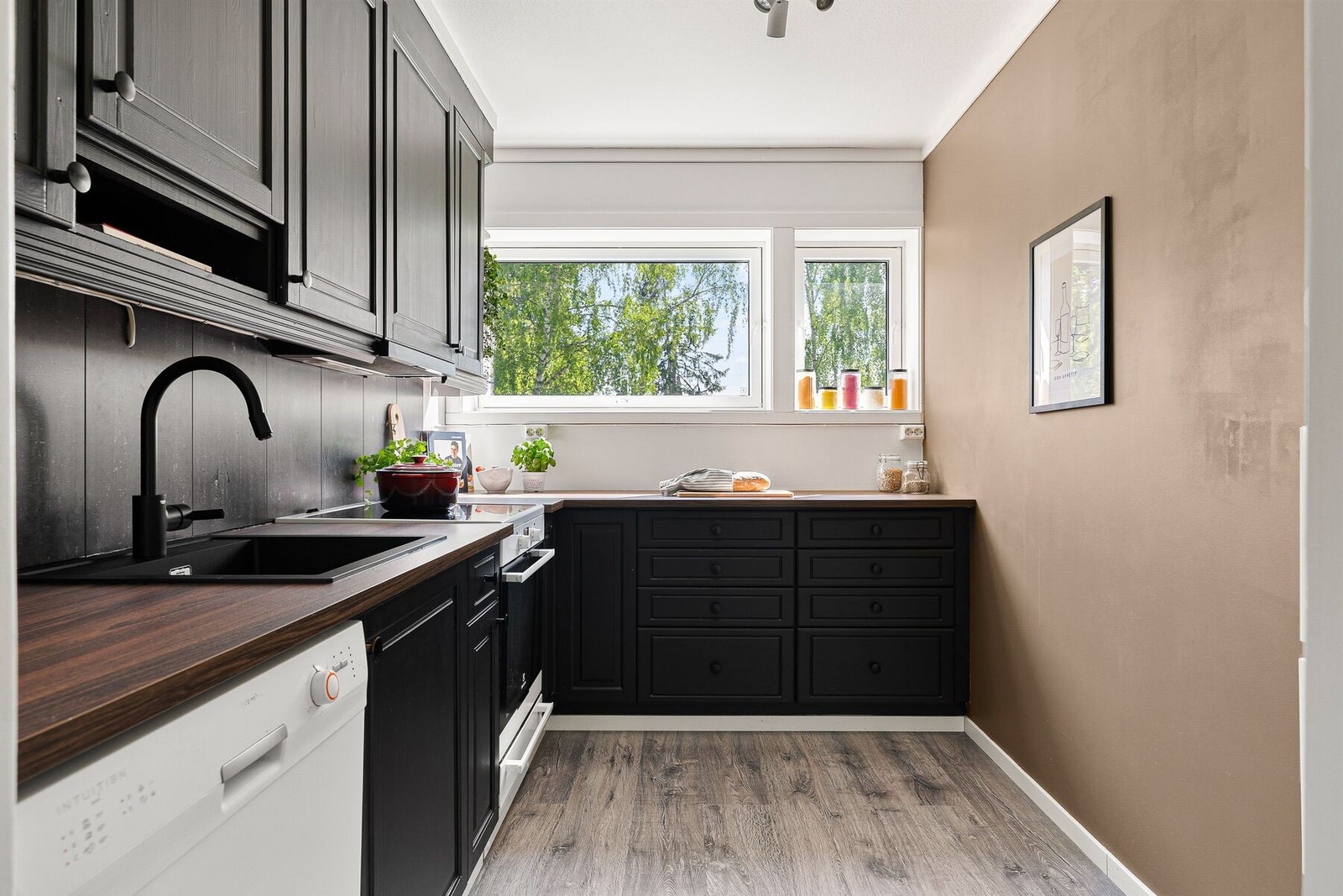 Pent og stilrent sort kjøkken som i nyere tid er oppgradert med ny benkeplate, vask, armatur og malte fronter. Galleribilde