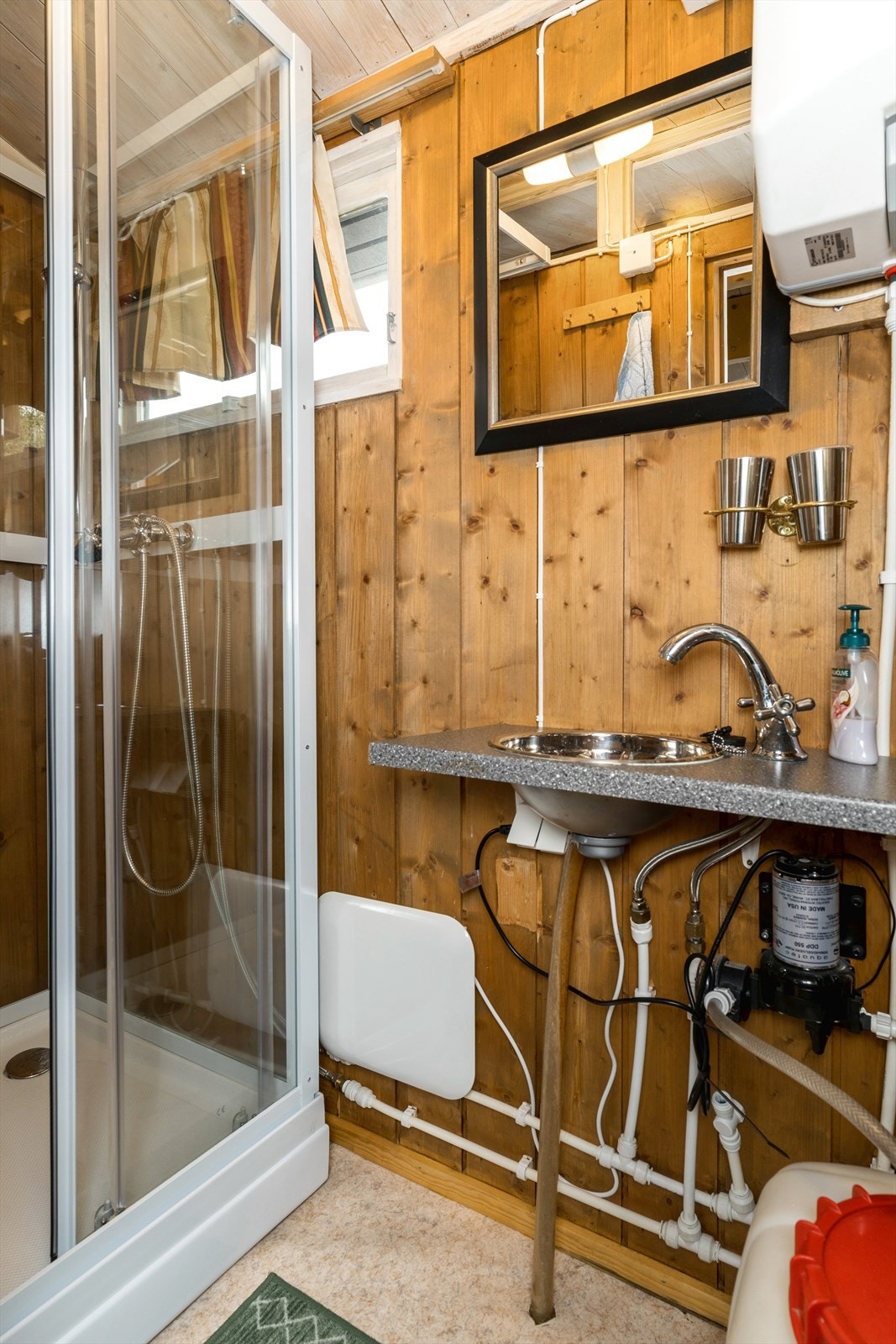 Enkelt hyttebad innredet med dusjkabinett og vask tilkoblet Vera vannsystem. Galleribilde