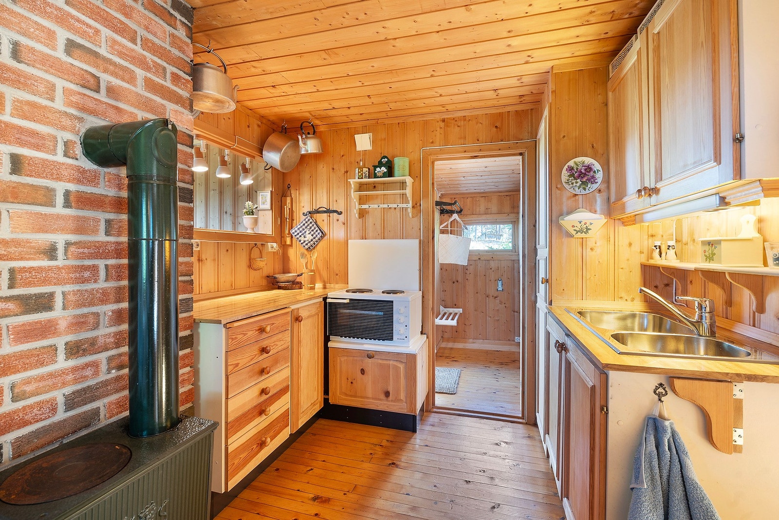 Kjøkkenet er delvis åpent mot stuen, med innsyn fra en smart gjennomgangsåpning som skaper praktisk kontakt mellom rommene Galleribilde