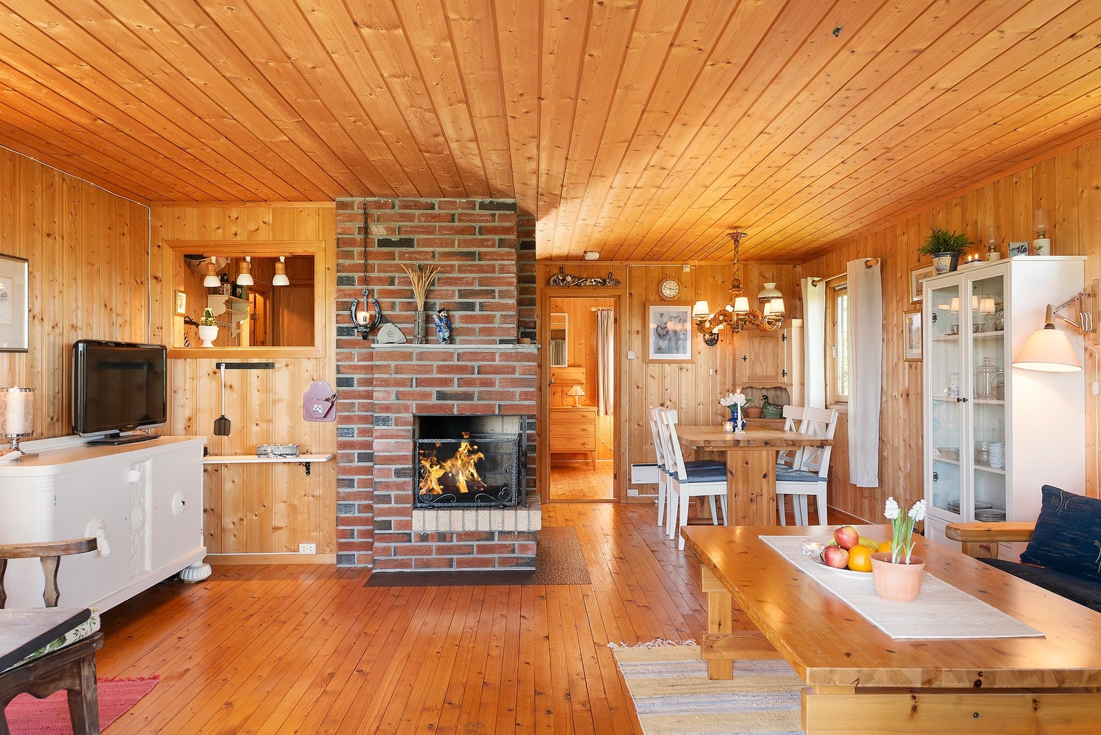 Midt i rommet står en solid, murt peis som gir lun varme og hyggelig atmosfære Galleribilde