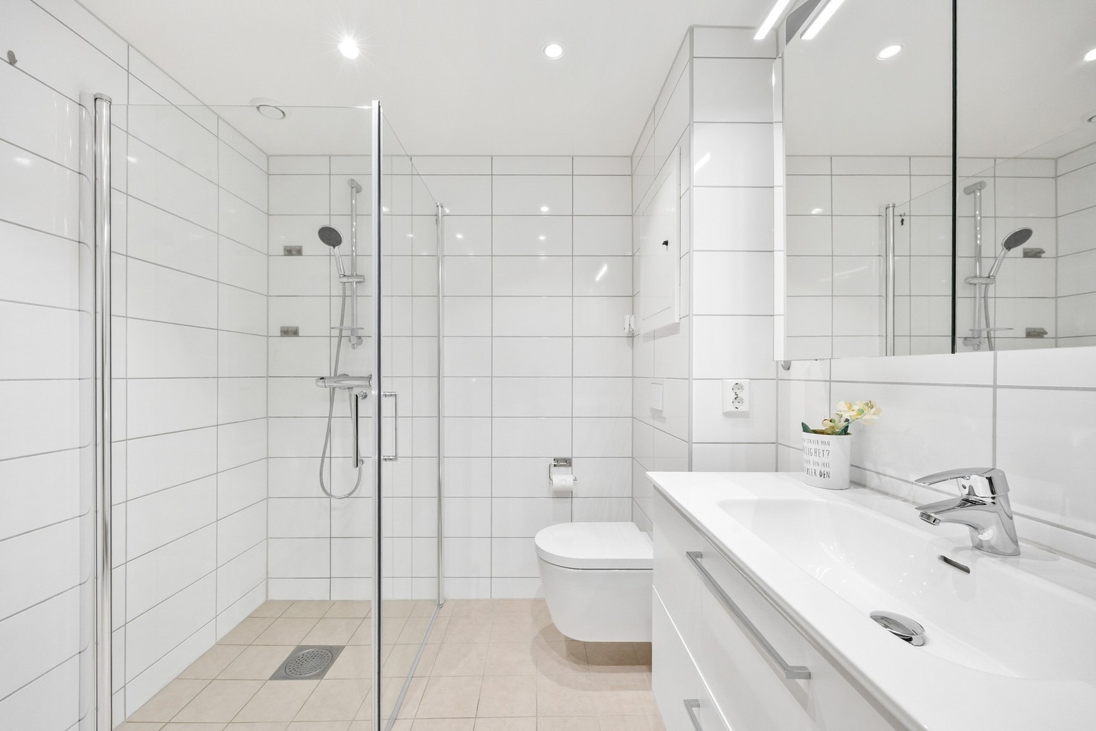 Badet inneholder servant, skap, vegghengt toalett og dusjsone. Galleribilde