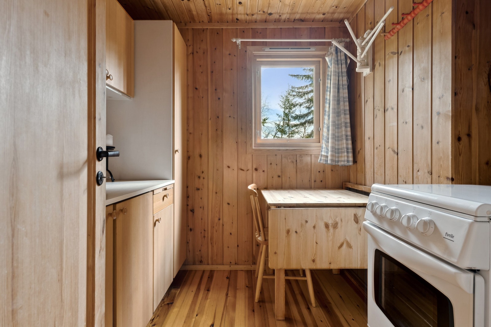 Enkelt innredet kjøkken med spiseplass og propankomfyr Galleribilde