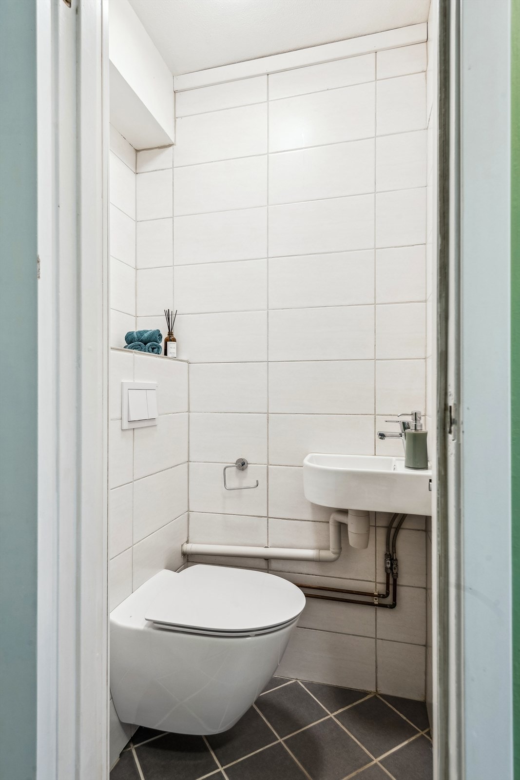 Toalettrommet ligger rett ved siden av badet og har fliser på gulv og vegger. Rommet har servant og vegghengt WC. Galleribilde