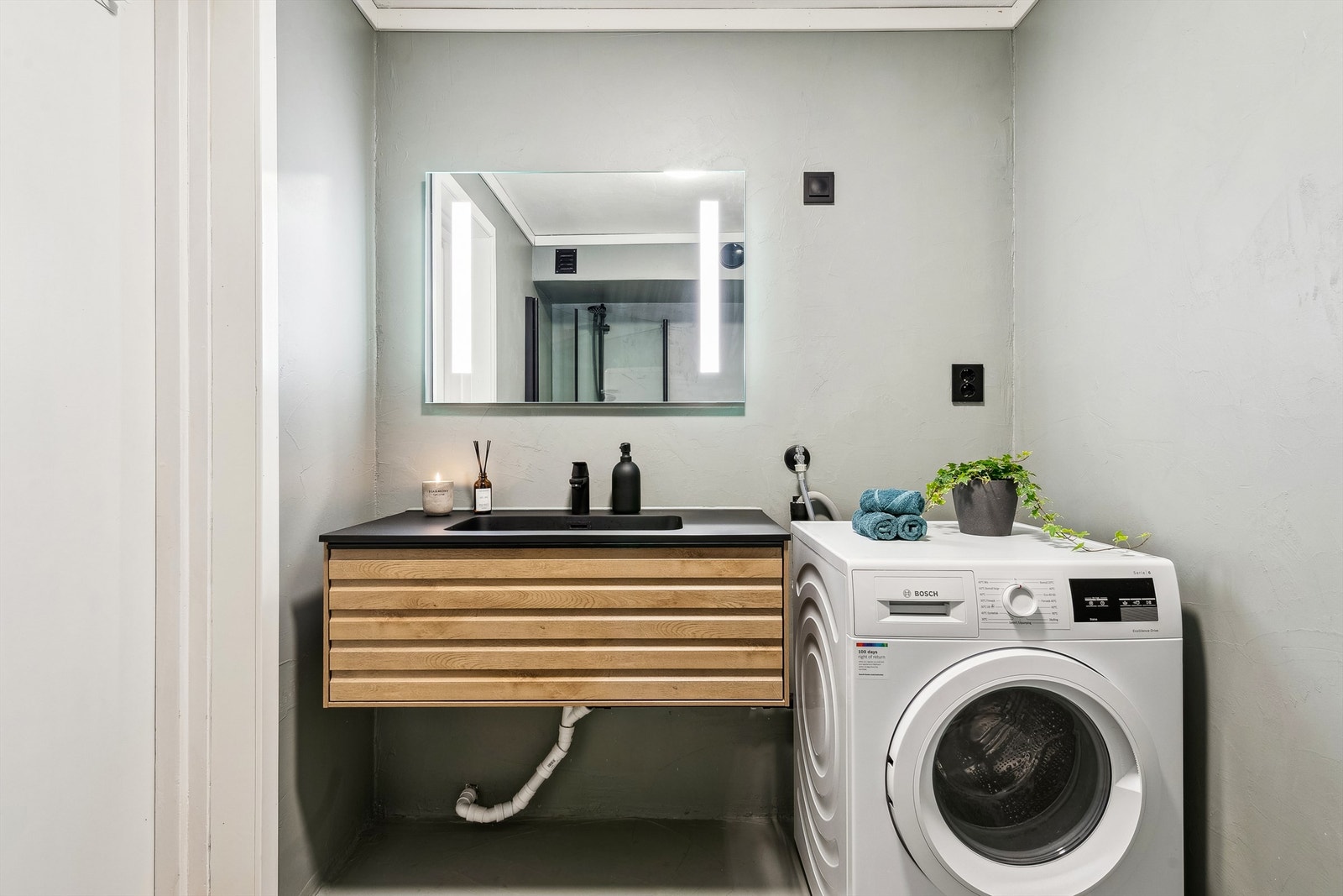 Badet er innredet med servant med underskap, dusjvegger og opplegg for vaskemaskin. Galleribilde