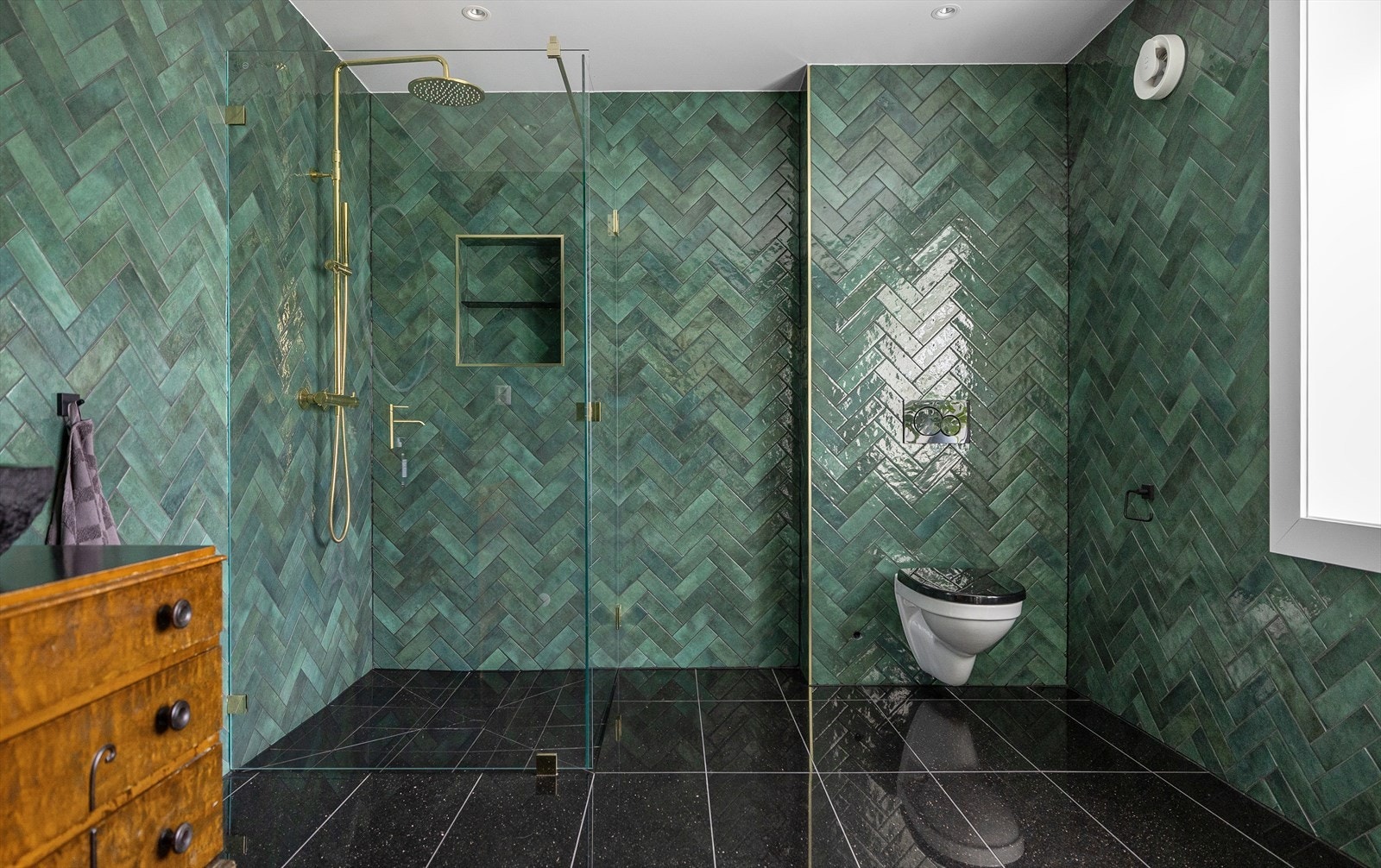 Ser vi på badet finner vi sjøgrønne veggfliser i fiskebeinsmønser og sorte høypolerte granittfliser på gulvet. Galleribilde