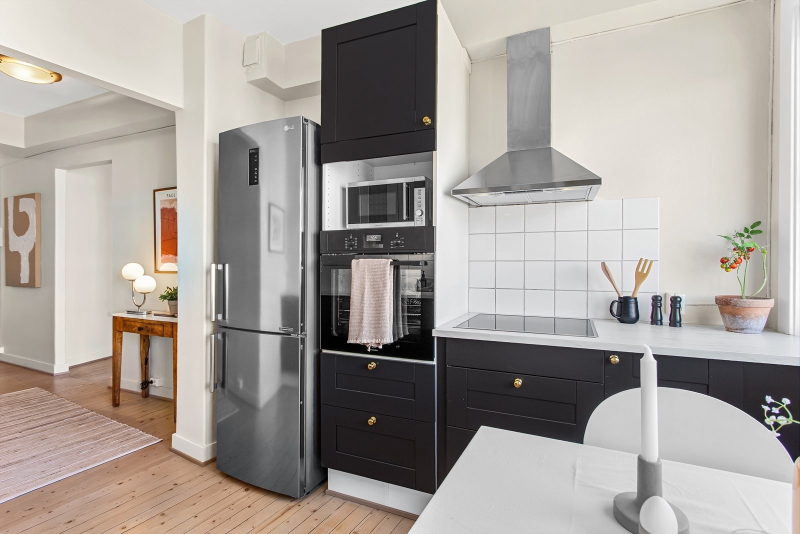 Malt kjøkkeninnredning, fliser over kjøkkenbenkene samt kullfilterventilator over platetopp Galleribilde