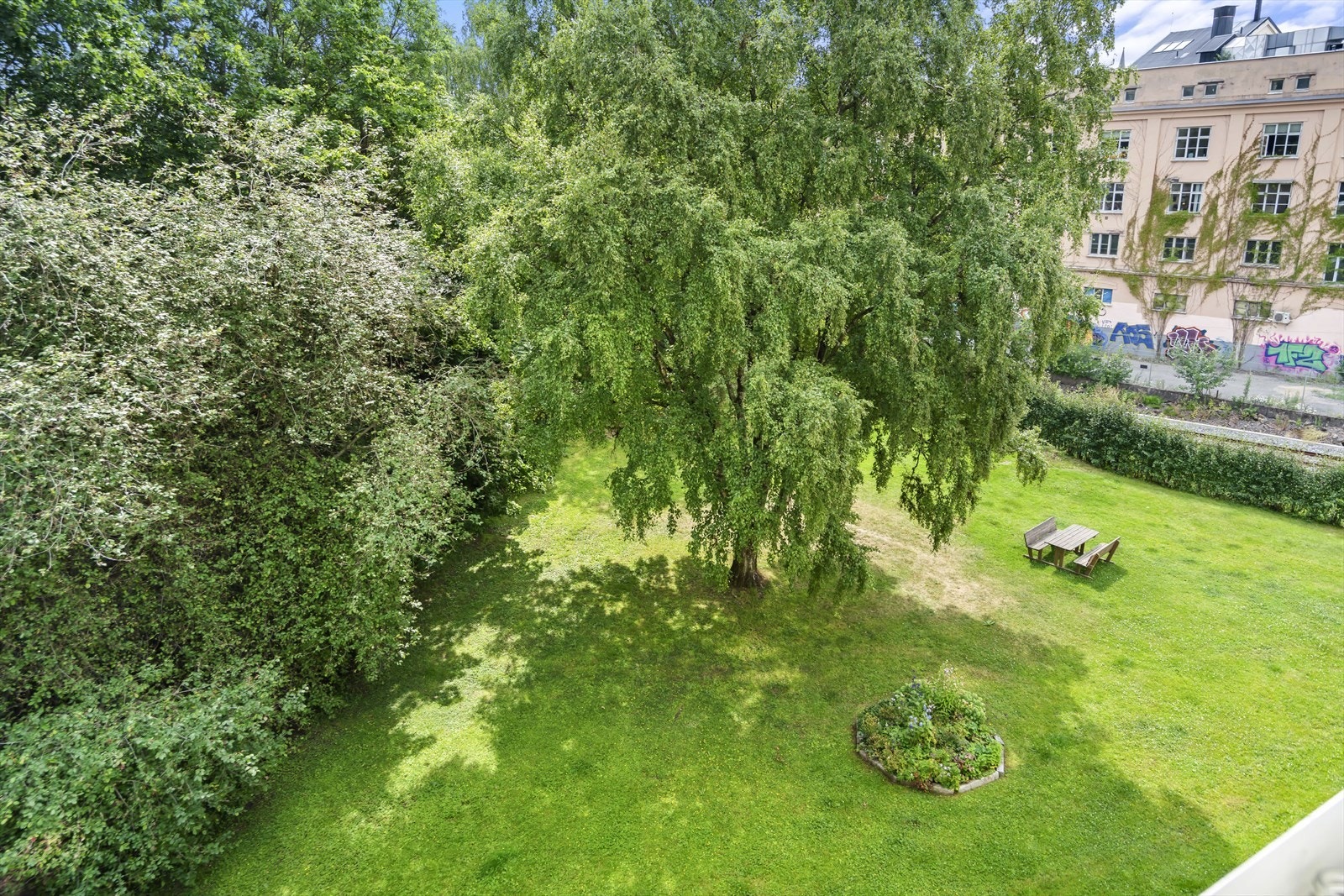 Fra balkongen er det åpent og frodig utsyn mot borettslagets fellesarealer. Galleribilde