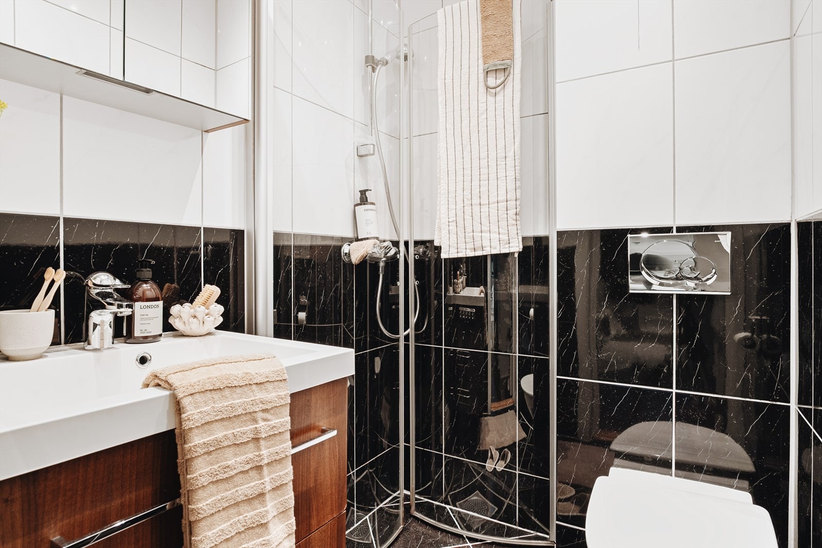 Badet er helfliset og rommer vegghengt toalett, helstøpt servant med slette fronter og dusjhjørne med glassdører. Funksjonelt og pent. Galleribilde