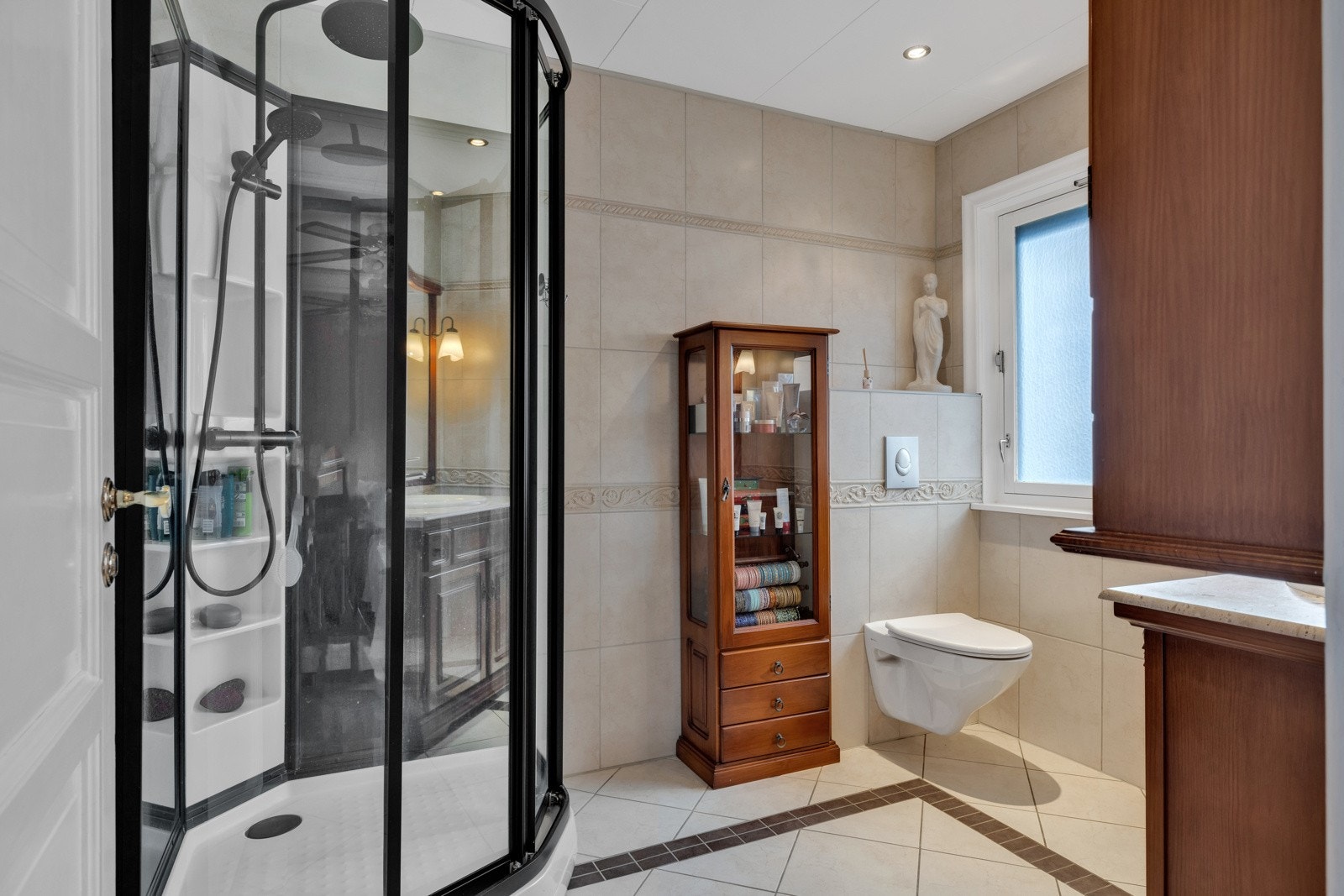 Flislagt baderom med dusjkabinett og veggfestet klosset Galleribilde