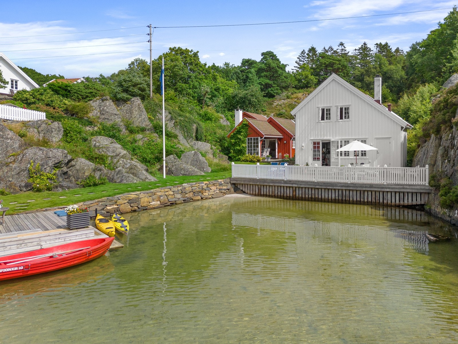 Hytten ligger fint plassert i terrenget innerst i bukten - med sandstrand foran Galleribilde