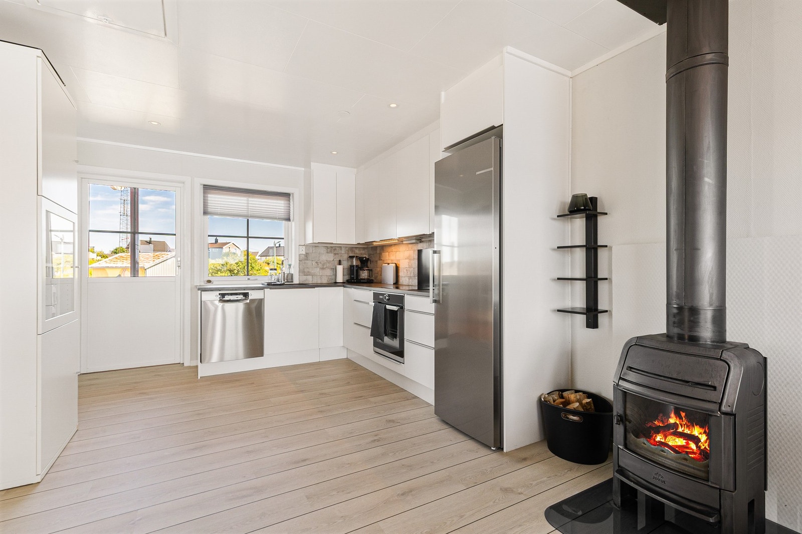 Pent kjøkken som holder et tidløst preg med sine hvite slette fronter Galleribilde