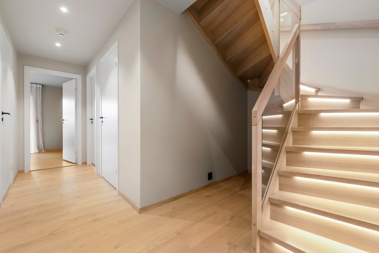 I underetasjen holdes fremdeles den samme elegante stilen. Lyssetting i trappetrinnene og glassfelt i rekkverket. PS ! Lagringsplass under trapp. Galleribilde