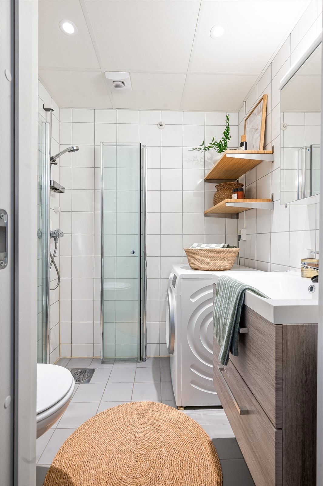 Badet er innredet med vegghengt klosett, servant med innredning, speilskap og dusjhjørne med svingbare glassdører. Galleribilde