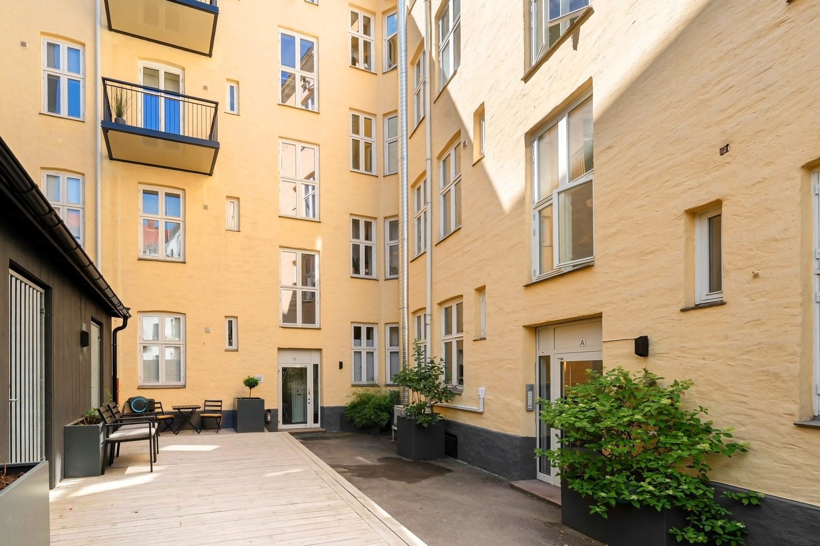 Skjermet og pent opparbeidet gårdsrom med beplantning og sittegruppe. Galleribilde