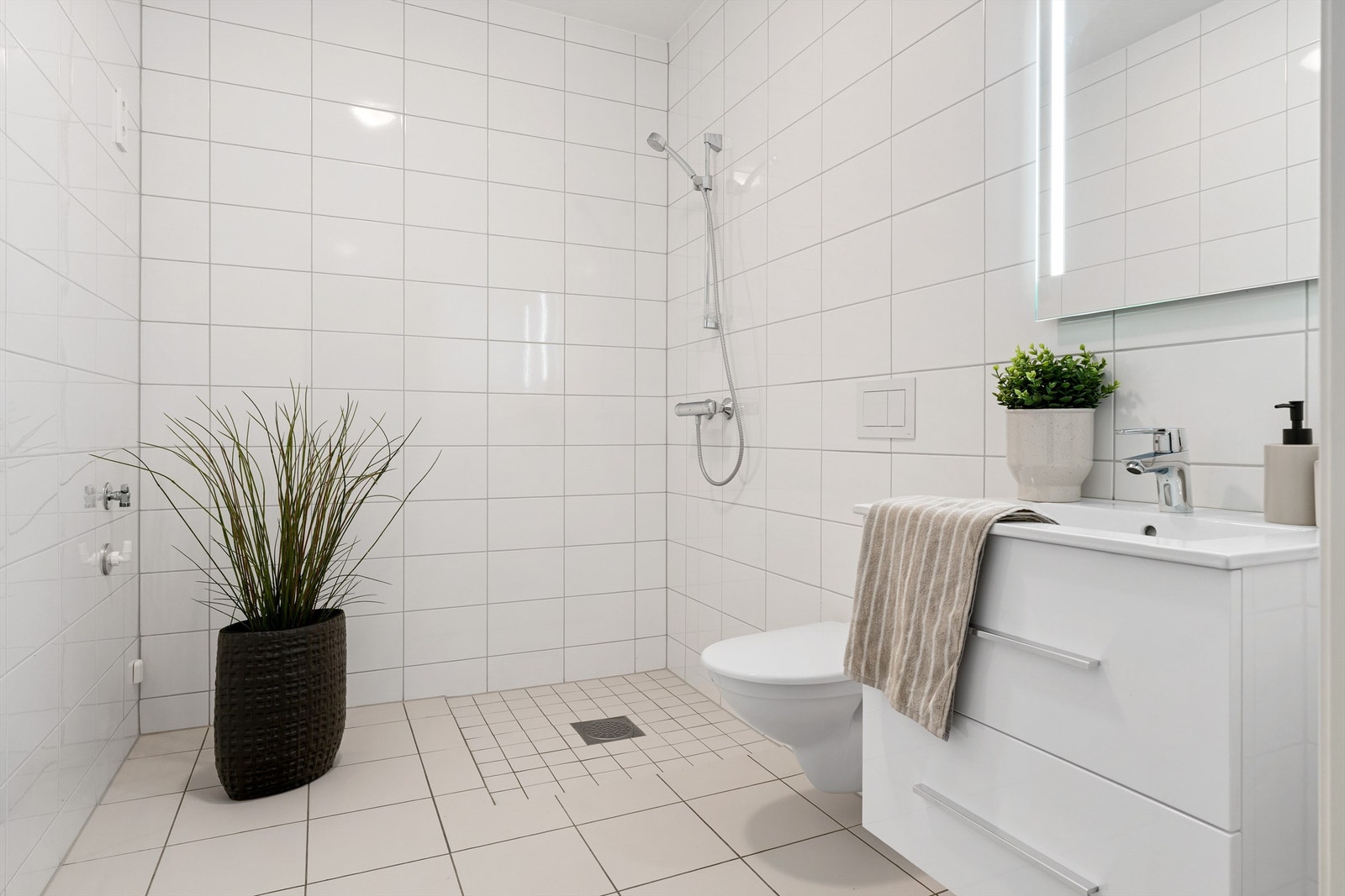 Badet i 1. etasje er innredet med flislagte flater, opplegg for vaskemaskin og gulvvarme. Galleribilde