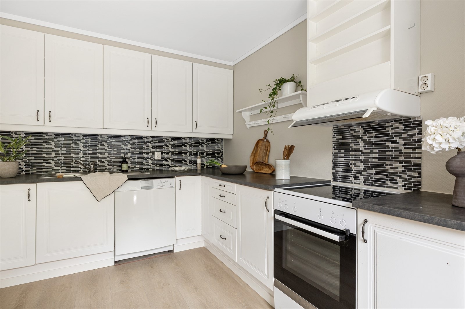 Kjøkkeninnredning med profilerte fronter, benkeplate i laminat og nedfelt stålvask med skyllekum, avrenningsbrett og ett-greps blandebatteri. Galleribilde