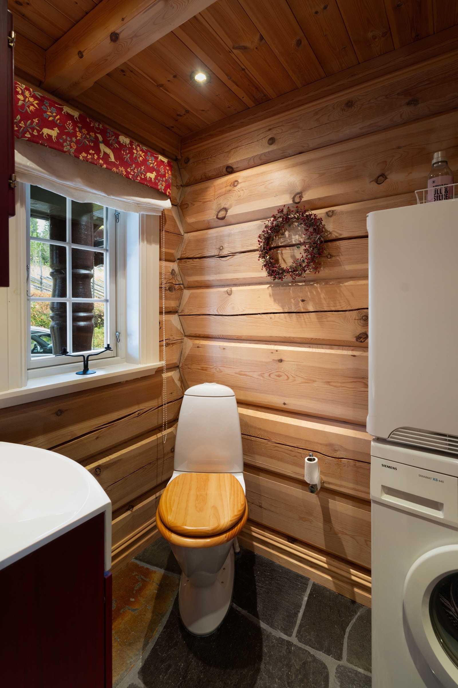 Mindre toalettrom i gangen med gjestetoalett, servant med overskap og opplegg for vaskemaskin og tørketrommel. Galleribilde