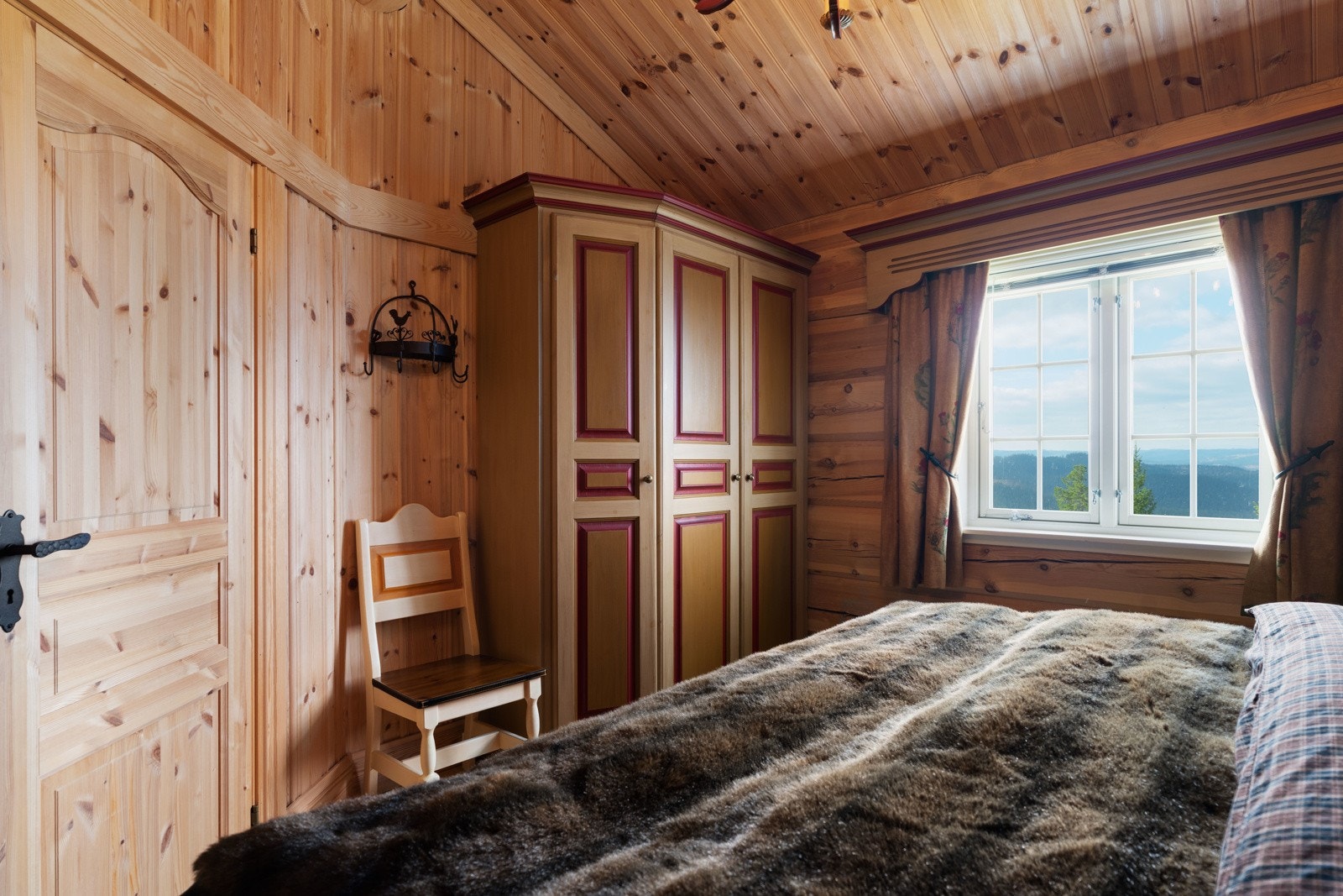 Dobbeltsengen er omkranset av en plassbygd tradisjonell sengegavl med detaljerte utskjæringer slik som servanten på badet. I fotenden av sengen er det satt opp et plassbygd garderobeskap i tilsvarende stil. Galleribilde